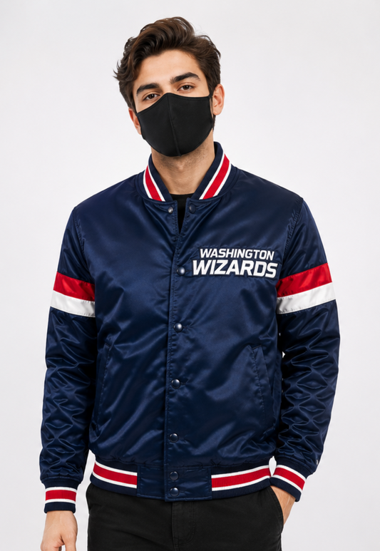 A man wearing a navy blue satin bomber jacket with 'WASHINGTON WIZARDS' printed on the chest, featuring red and white striped ribbed collar, cuffs, and hem, paired with a black face mask.