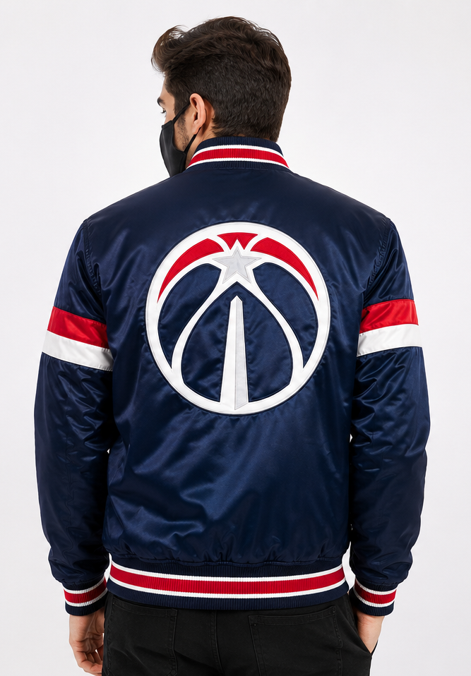 A man viewed from the back wearing a navy blue satin bomber jacket with red and white stripes on the collar, cuffs, and hem, featuring a large Washington Wizards logo on the back.