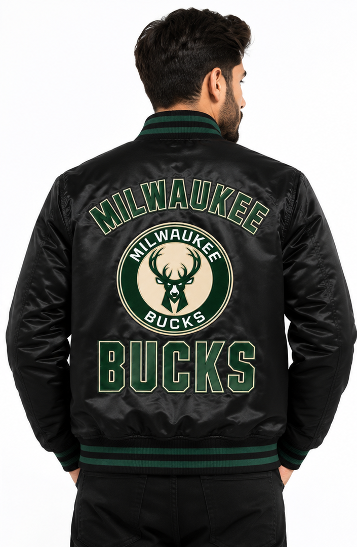 A man viewed from behind wearing a black Milwaukee Bucks satin bomber jacket with a large green and beige team logo and text on the back, set against a plain white background.