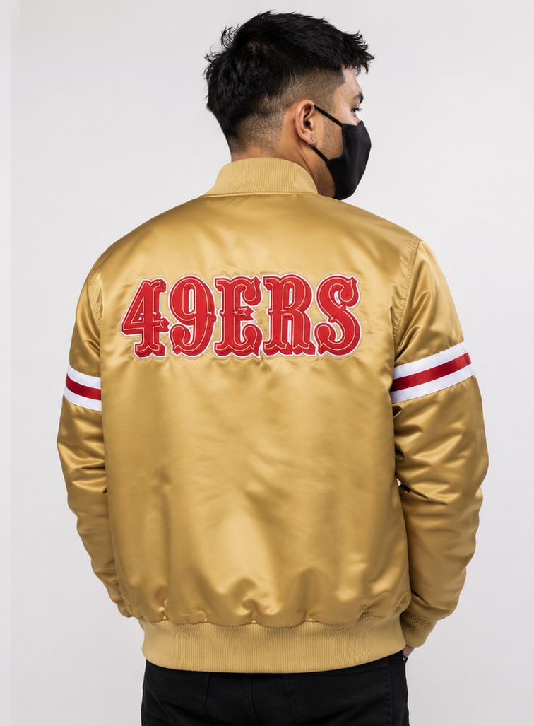Person wearing a San Francisco 49ers gold jacket with '49ERS' text on the back against a white background