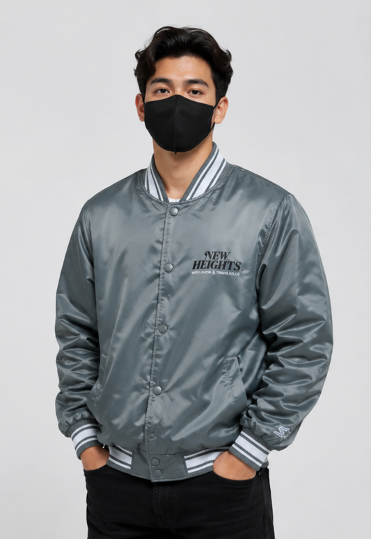 A man wearing the New Heights 92%ers Gray Satin Jacket with team logos on a white background