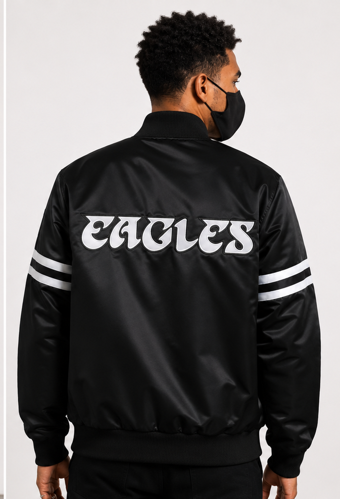 Person wearing a Philadelphia Eagles black 'EAGLES' jacket on a white background