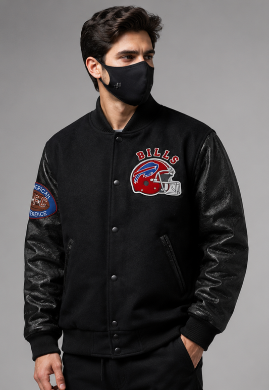 A man wearing a black varsity-style jacket with black leather sleeves, featuring a Buffalo Bills helmet patch on the left chest and a service patch on the right sleeve, posed against a solid gray background.