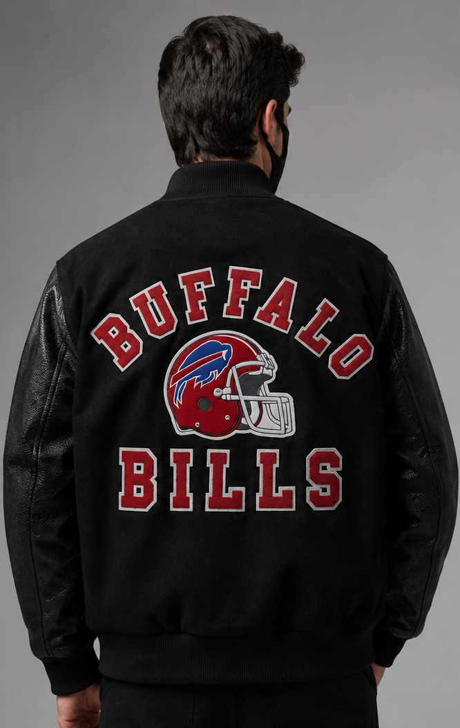 A man viewed from behind wearing a black Buffalo Bills varsity-style jacket with red and white embroidered lettering and a team helmet graphic on the back, against a neutral gray studio background.