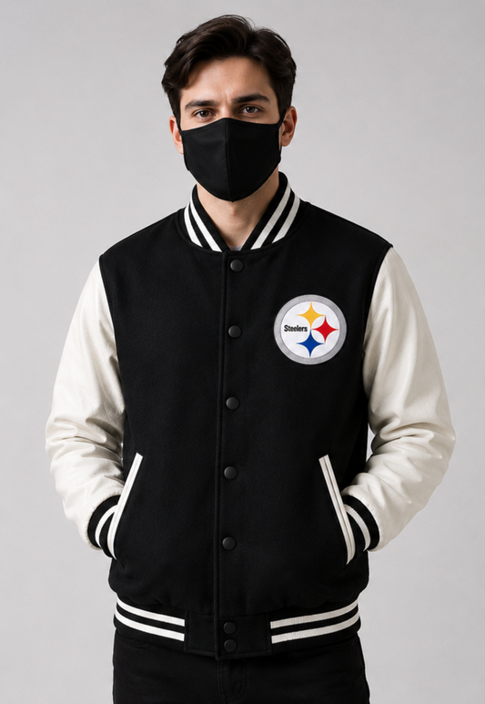 A man wearing a black and white varsity jacket with the Pittsburgh Steelers logo on the chest, paired with a black face mask, against a neutral gray background.