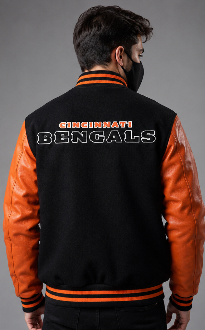 A man viewed from the back wearing a black and orange varsity jacket with 'CINCINNATI BENGALS' embroidered on the back, set against a plain gray studio background.