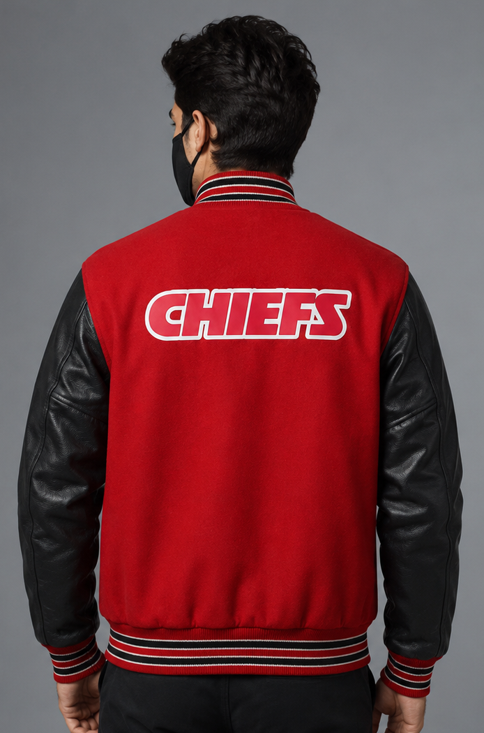 A man viewed from the back wearing a red and black varsity jacket with 'CHIEFS' embroidered in white on the back, set against a solid gray studio background.