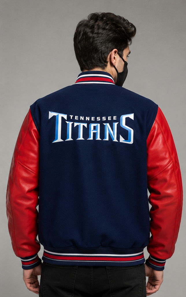 A man viewed from the back wearing a navy blue and red varsity jacket with 'TENNESSEE TITANS' embroidered on the back, set against a plain gray studio background.