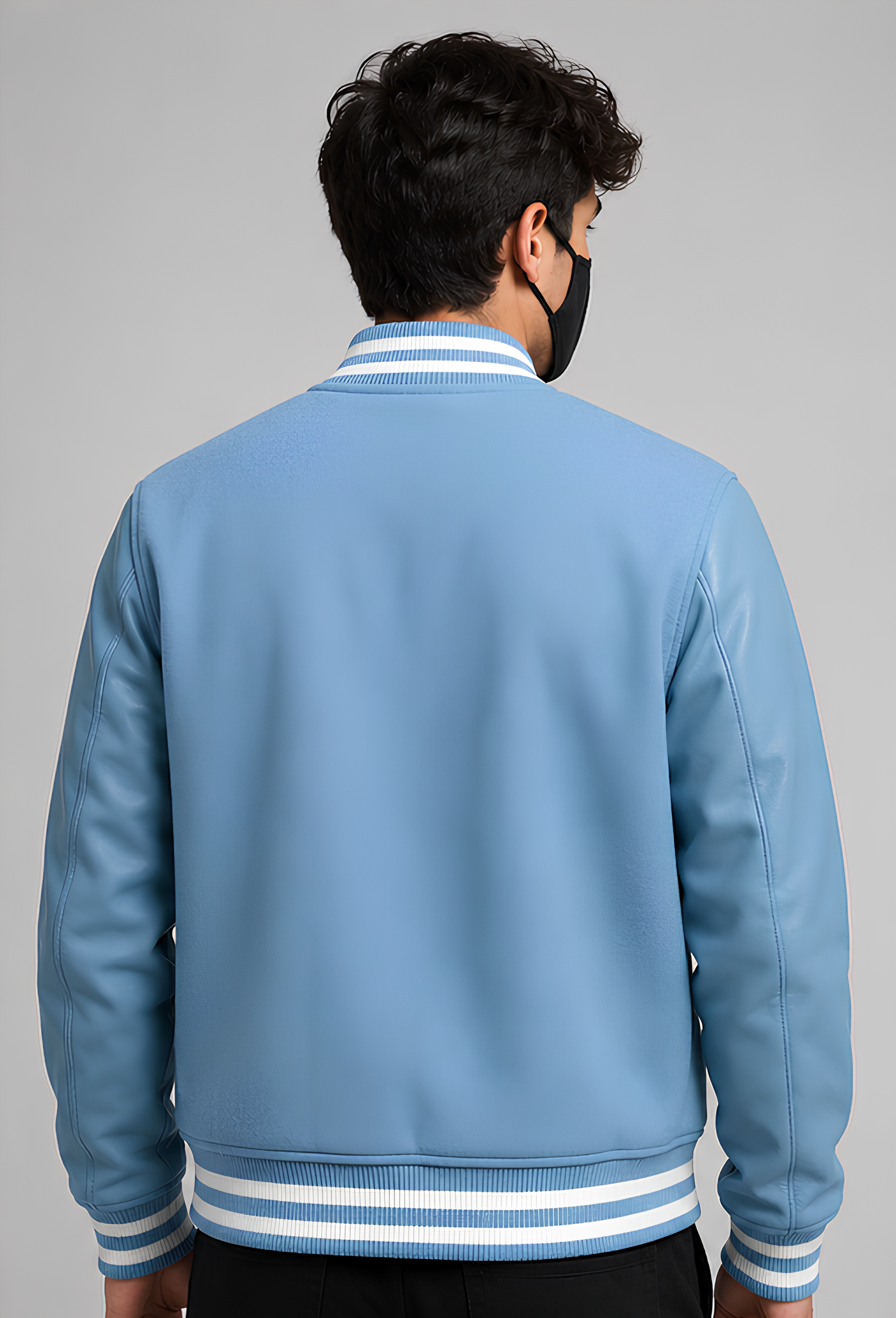Person wearing a light blue varsity jacket with white stripes on a gray background