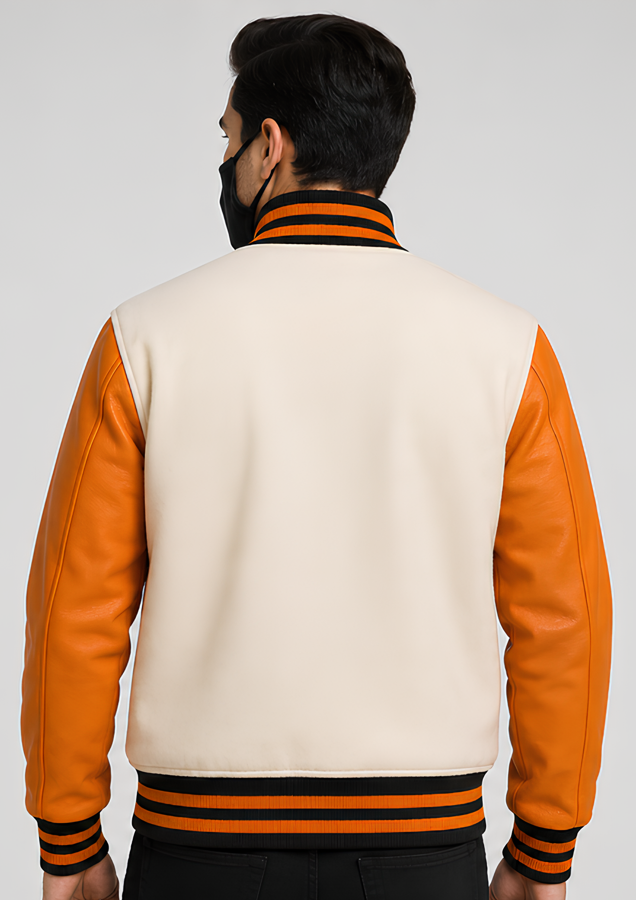 Person wearing a white and orange varsity jacket with black accents on a plain background