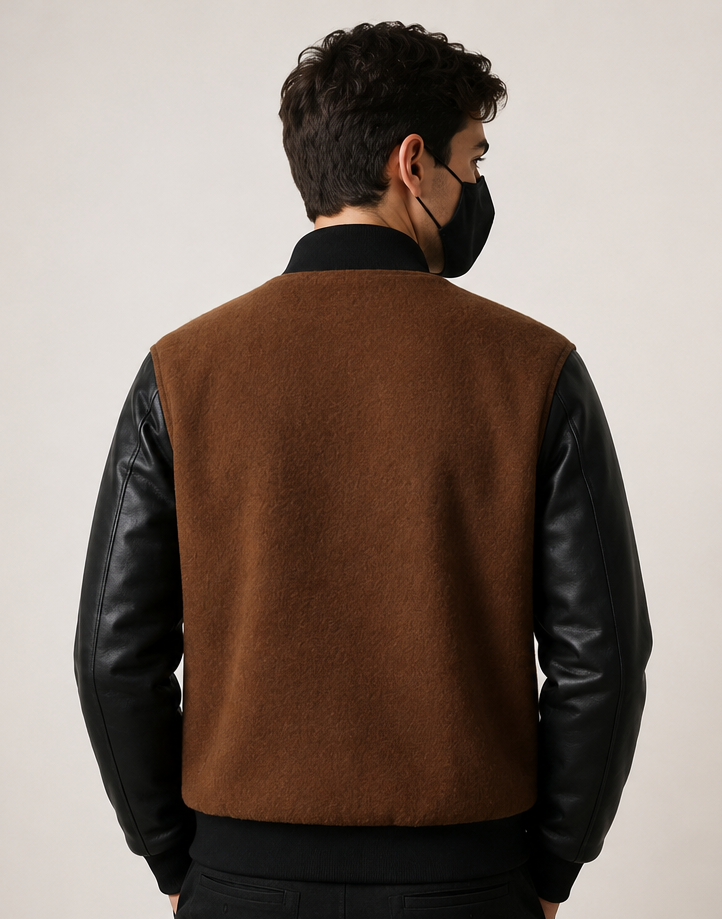 Person wearing a brown varsity with black sleeves on a plain background