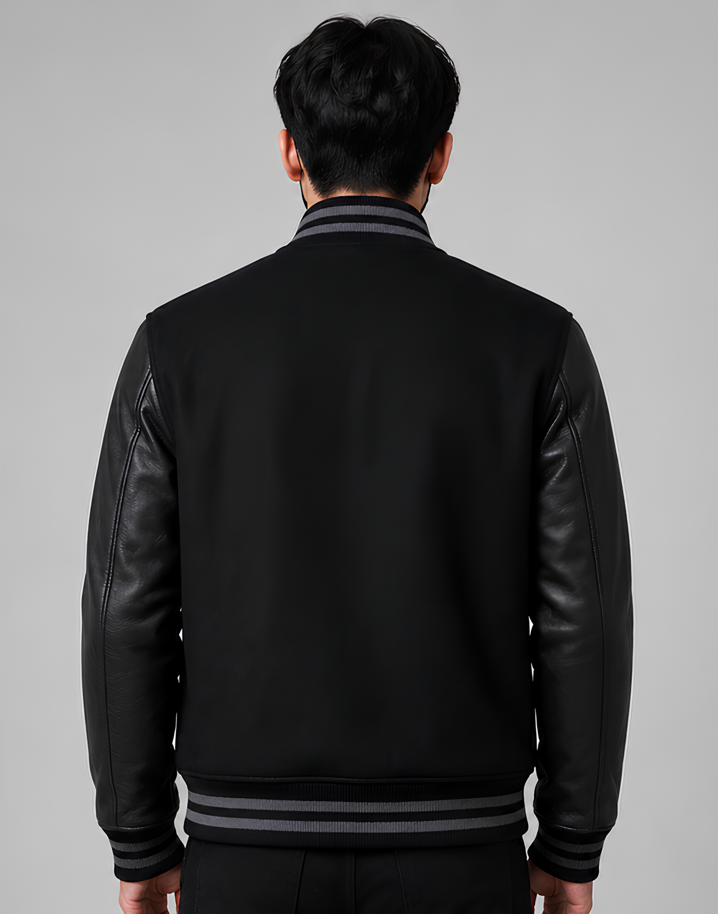 Person wearing a black leather jacket with gray trim on a gray background
