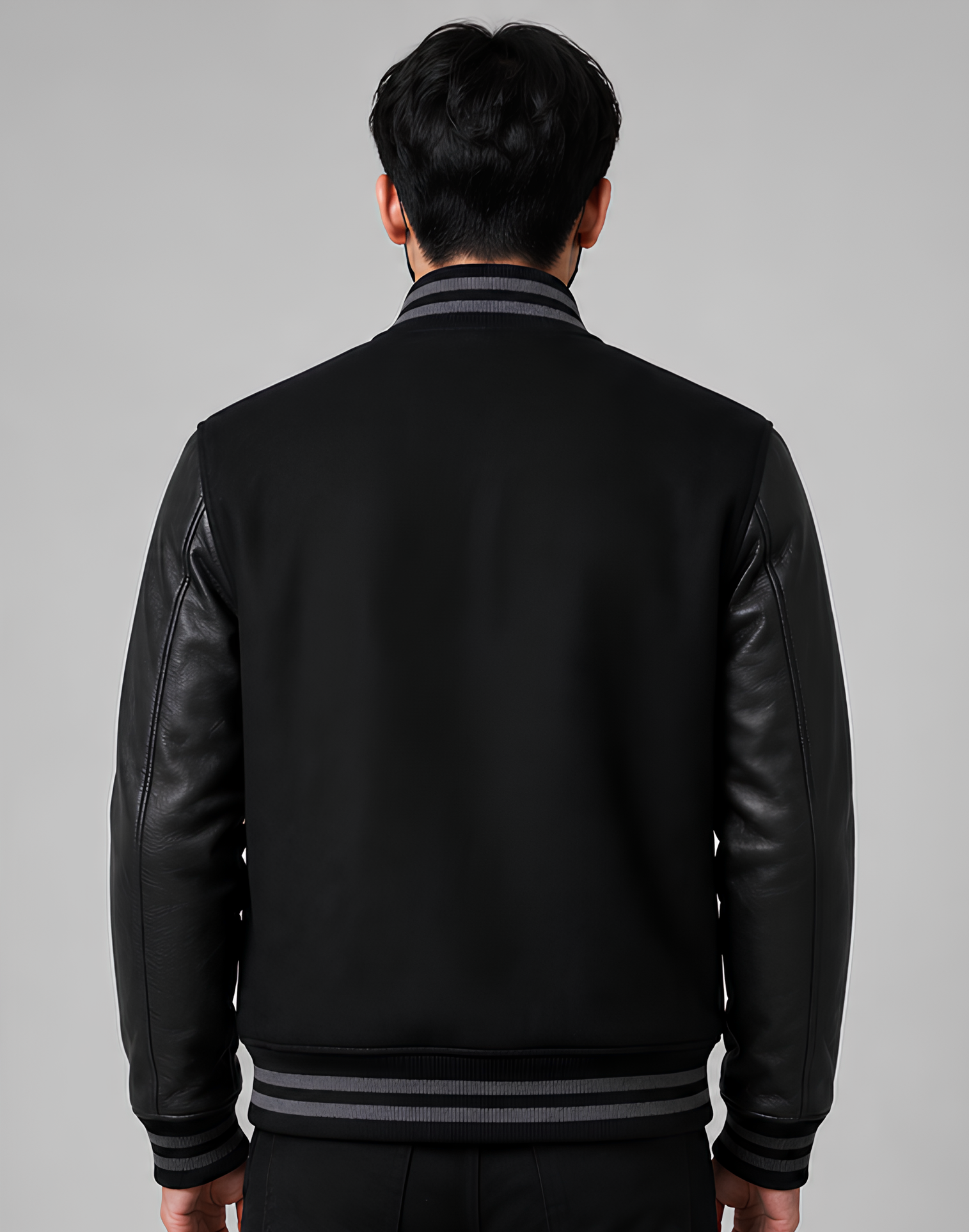 Person wearing a black leather jacket with gray trim on a gray background
