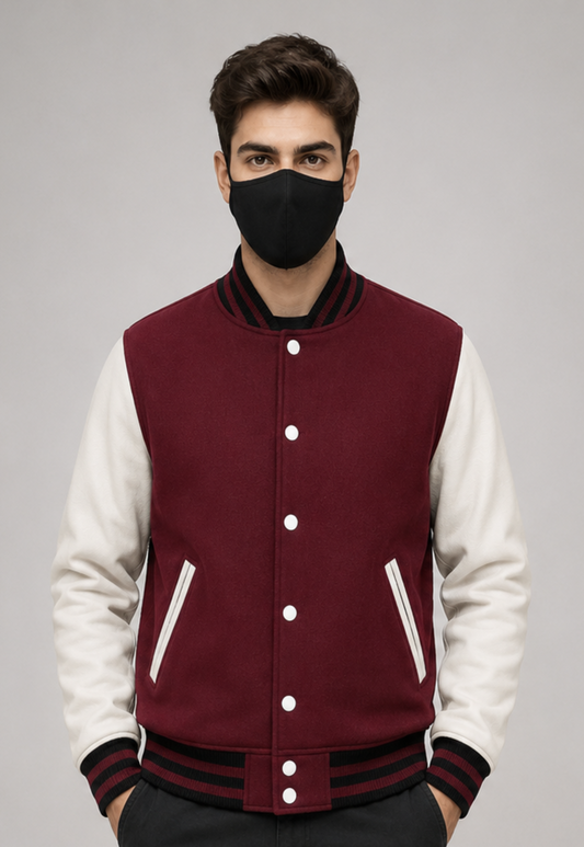 Person wearing a maroon and white varsity jacket with a black face mask on a gray background