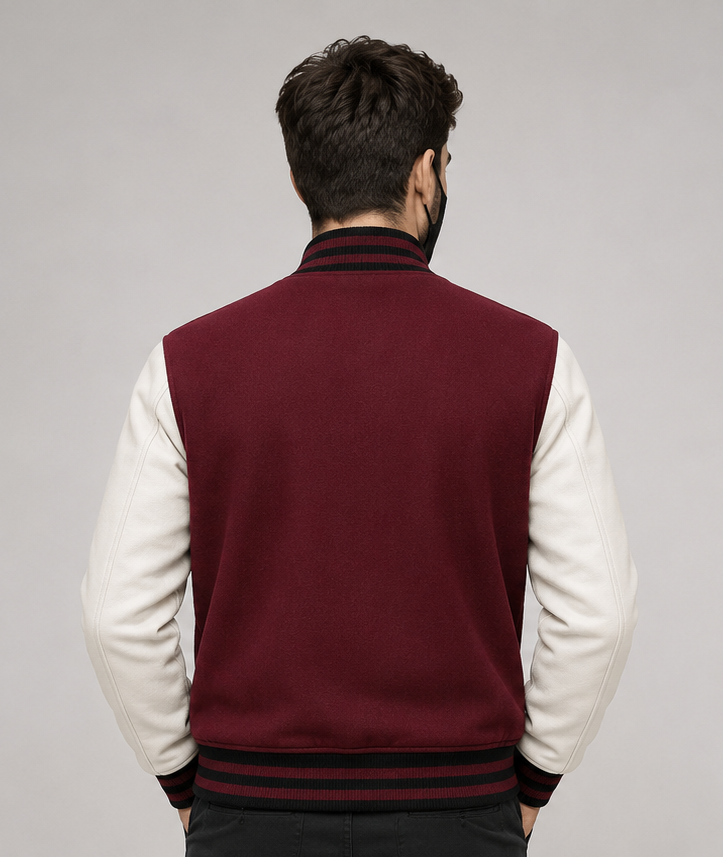 Man wearing a maroon and white varsity jacket on a gray background