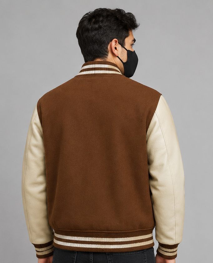 Man wearing a brown and beige varsity jacket on a gray background