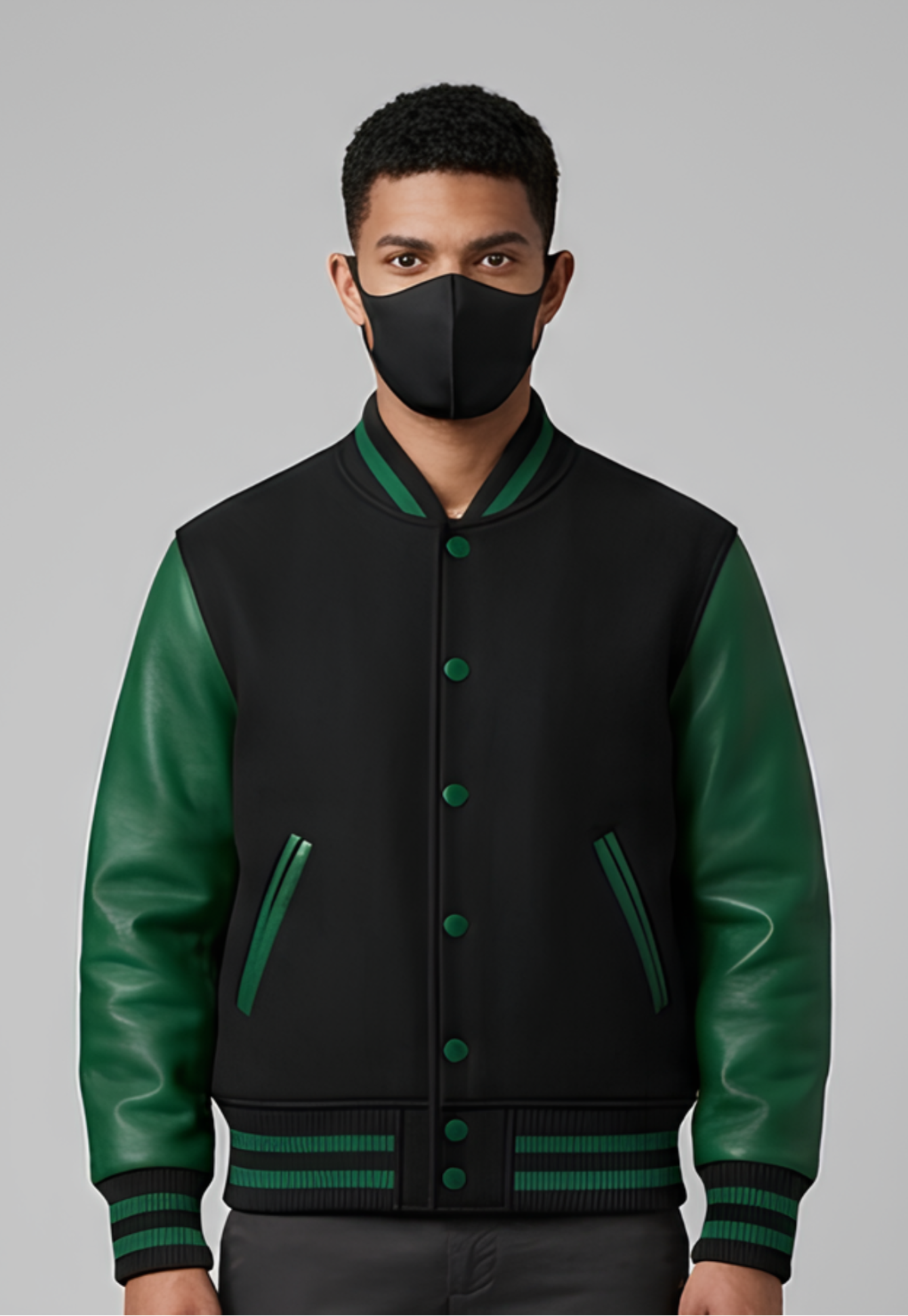 Person wearing a black and green varsity jacket with a plain background