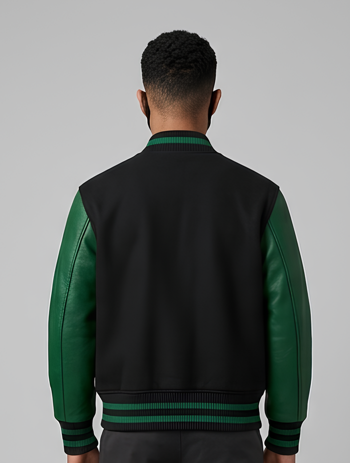 Person wearing a black and green varsity jacket on a gray background