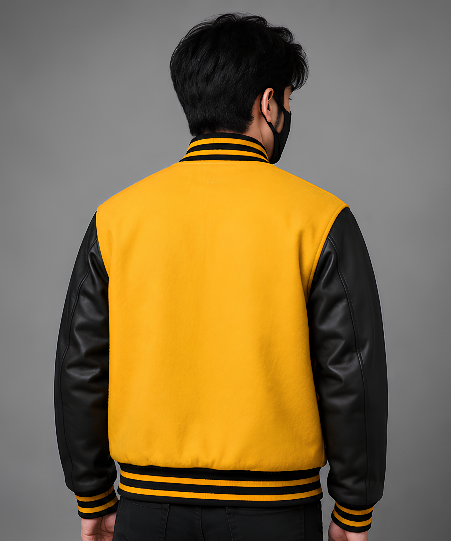 Person wearing a yellow and black varsity jacket on a gray background