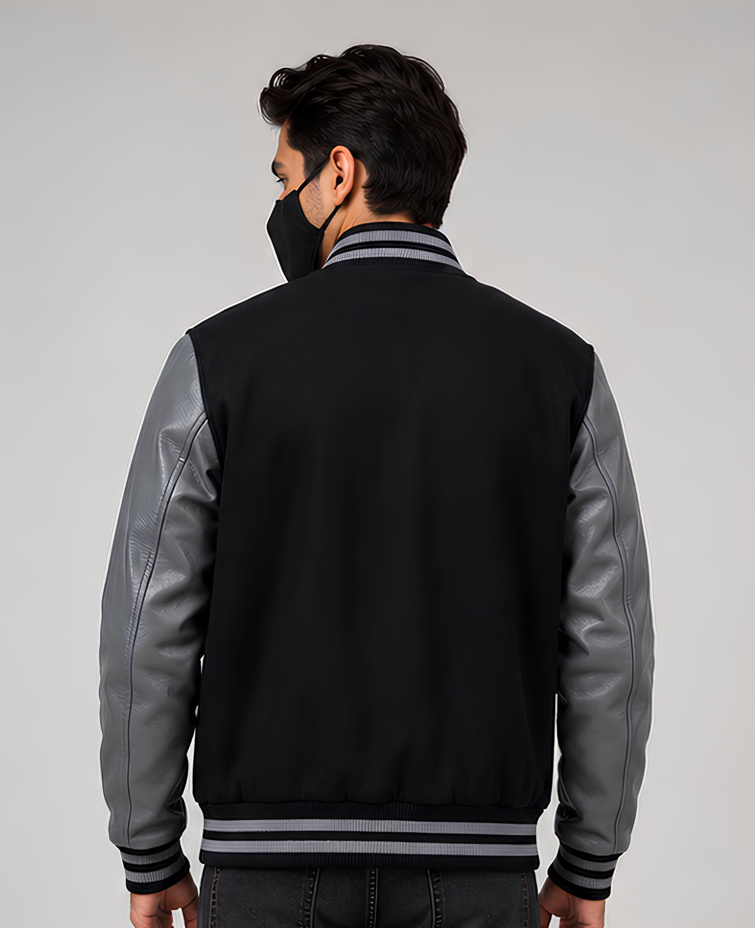 Person wearing a black and gray varsity jacket on a plain background