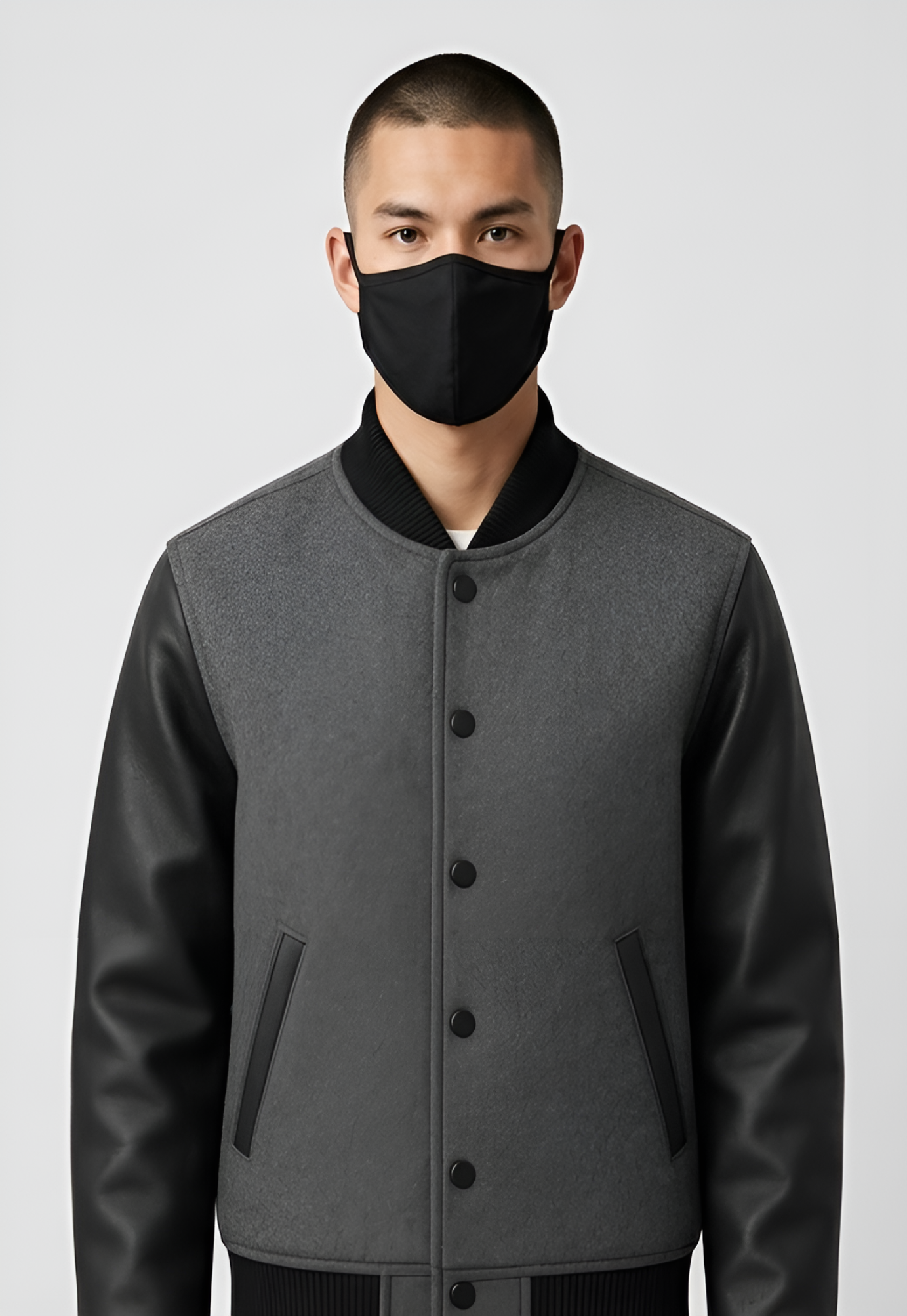Person wearing a gray varsity jacket with black accents on a white background