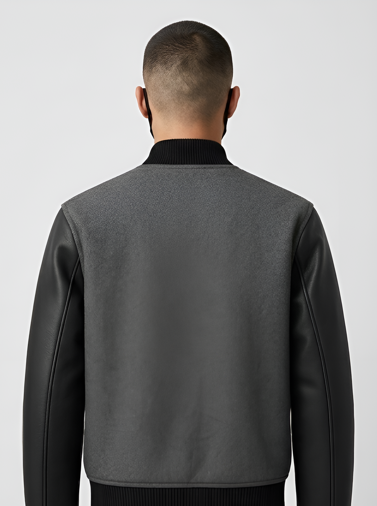 Person wearing a gray varsity jacket with black accents on a white background