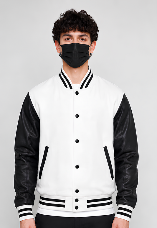 Person wearing a black and white varsity jacket with a plain background