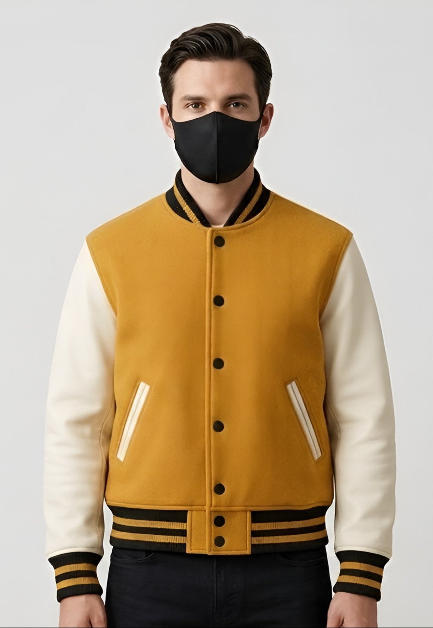 Man wearing a Golden and a white varsity jacket with black accents on a light gray background