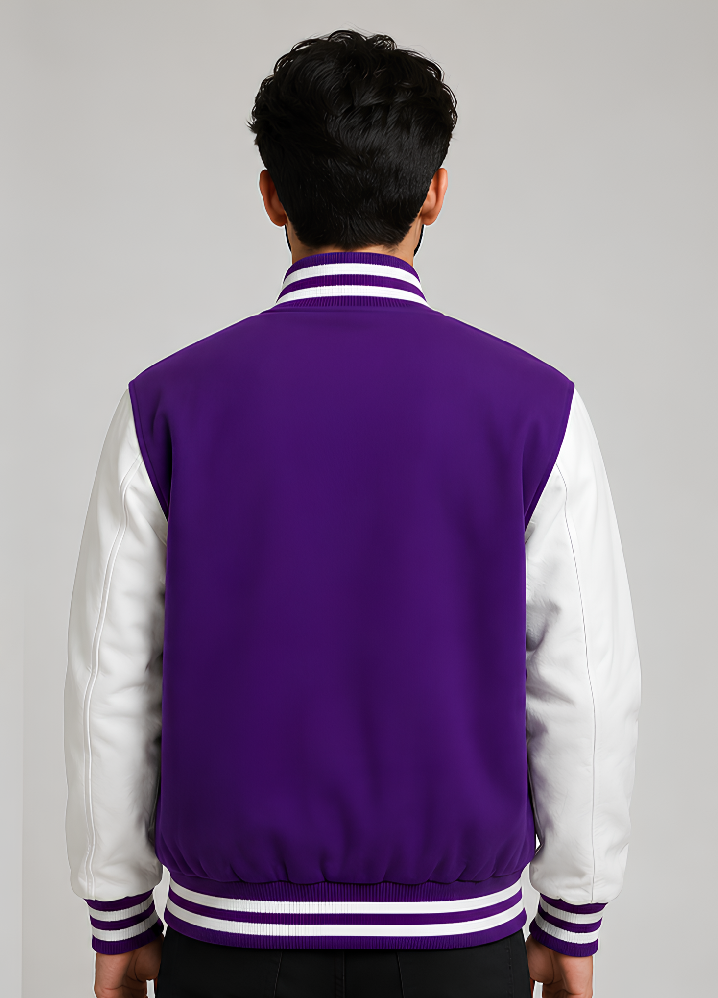 Person wearing a purple and white letterman jacket on a gray background