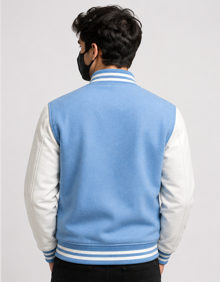 Person wearing a sky blue and white varsity jacket on a plain background