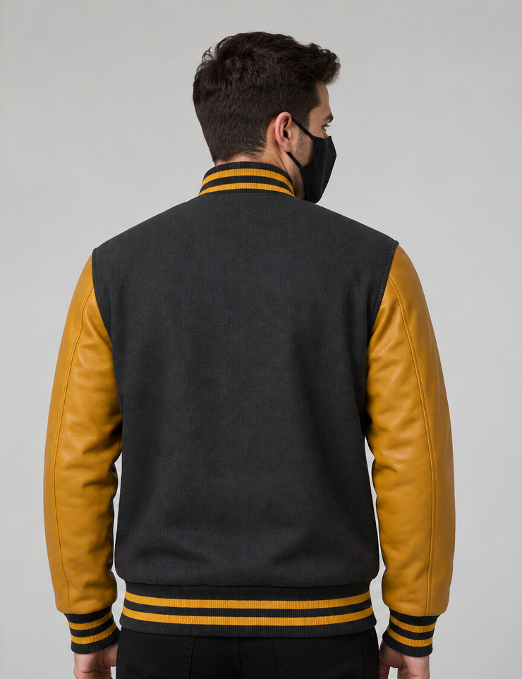 Man wearing a grey and golden varsity jacket on a grey background
