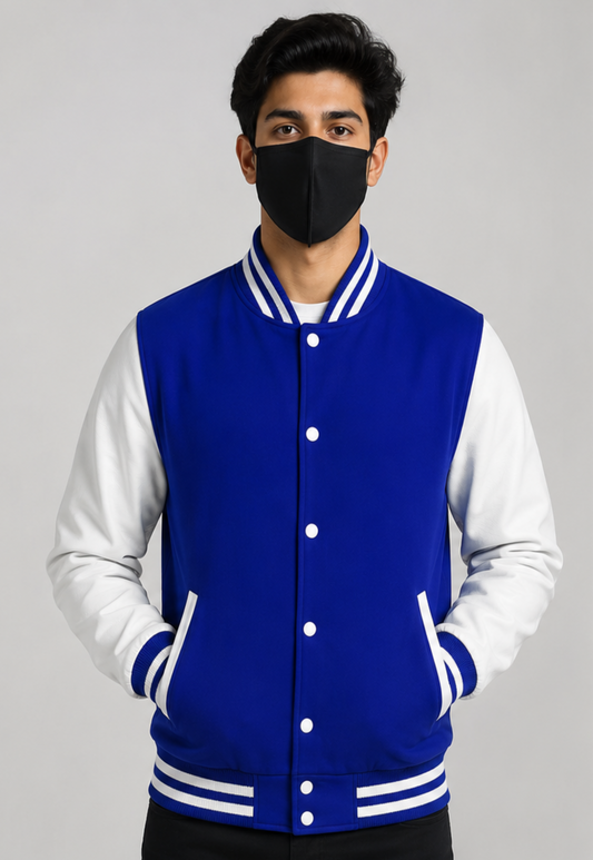 Person wearing a blue and white varsity jacket with a black face mask on a gray background