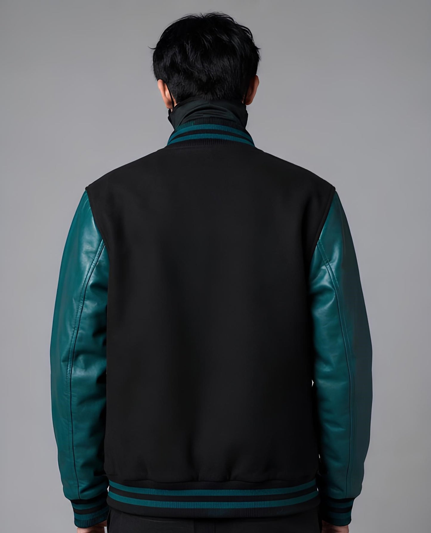 Person wearing a black and teal jacket against a gray background