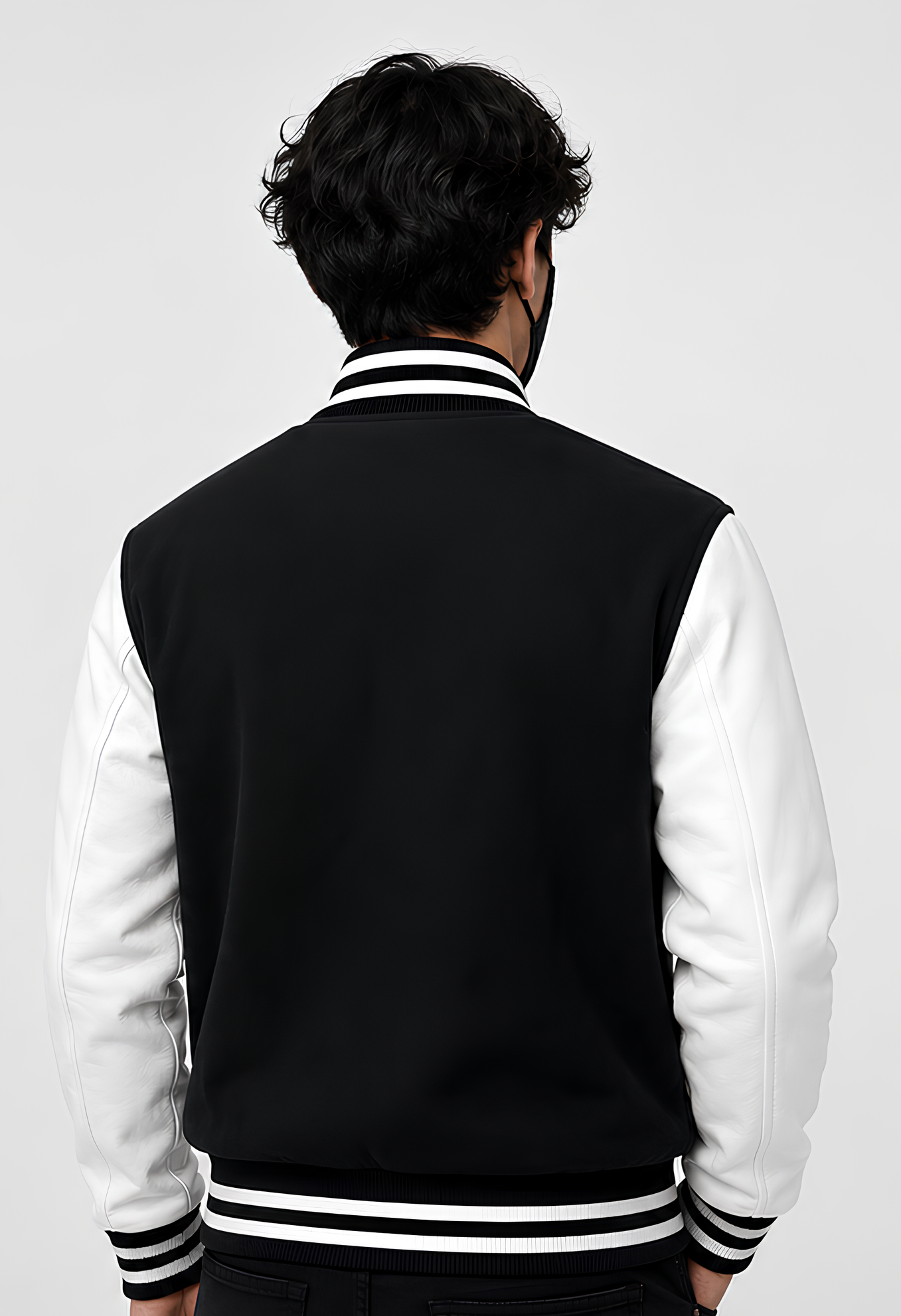 Person wearing a black and white varsity jacket on a plain background