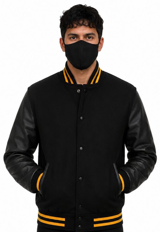 Person wearing a black varsity jacket with yellow accents and a black face mask on a white background